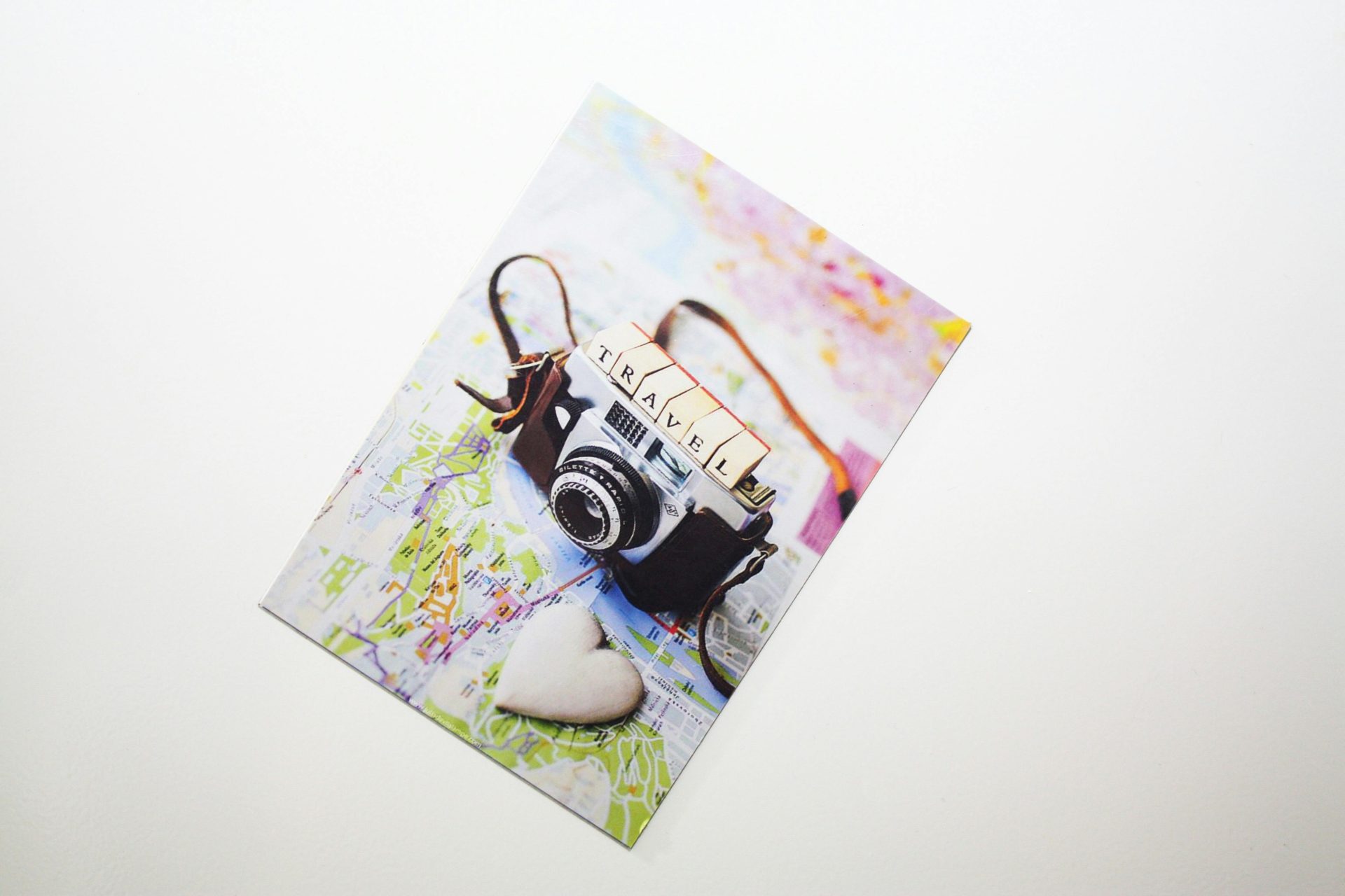 Flat lay of a vintage camera on a travel map with a heart shape, symbolizing travel passion.